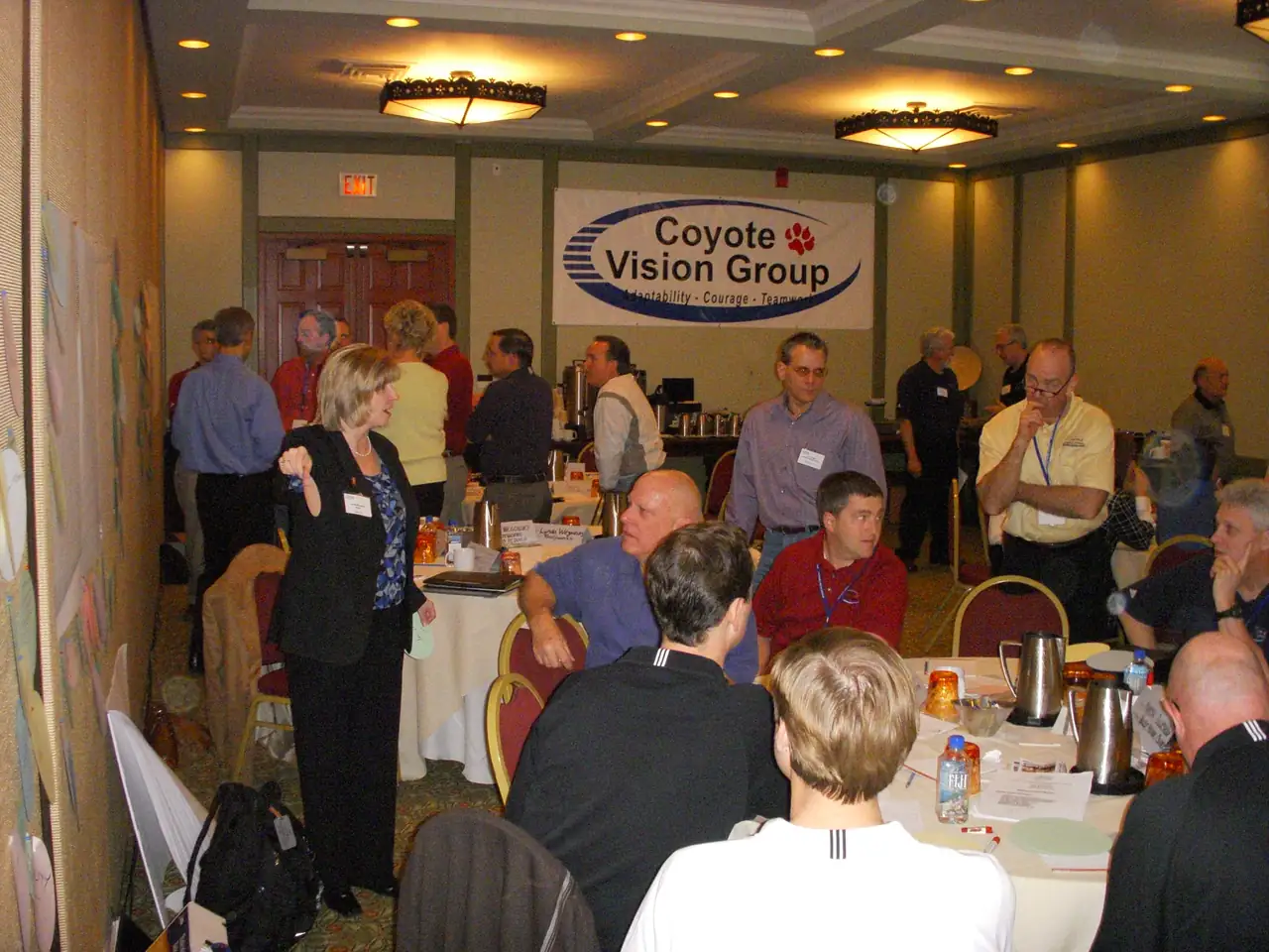Attendees at a Coyote Vision Group conference seated beneath the group's branded banner